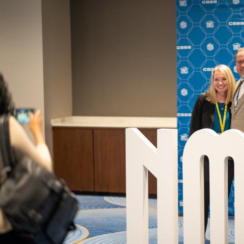 people standing behind NMLS sign